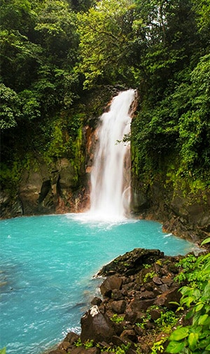 Rio Celeste waterfall - photo of a small waterfall in the rainforest with a sky blue pool.