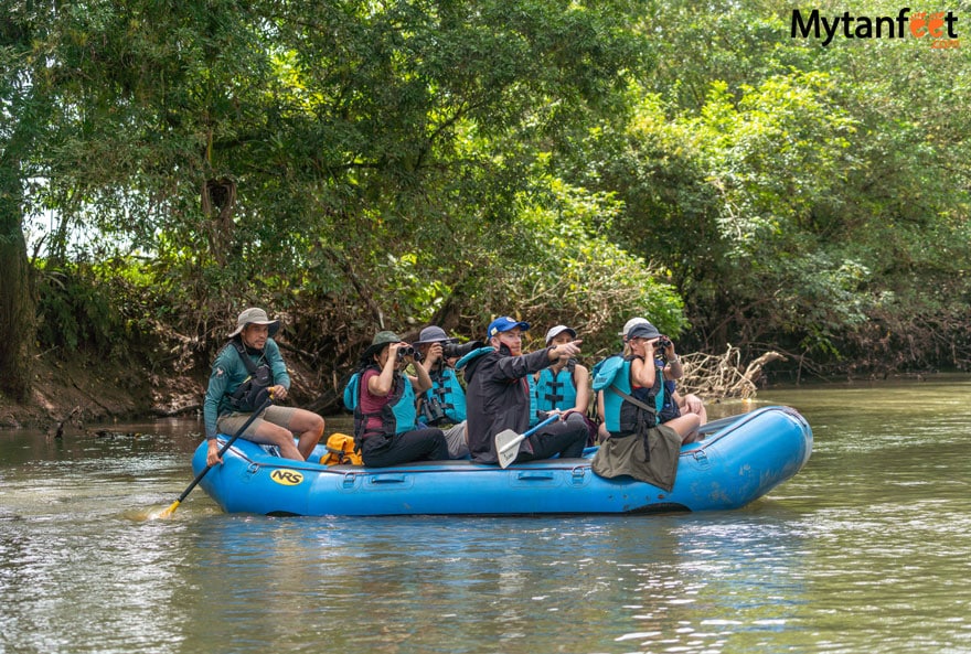 La Fortuna safari float - a group of 6 tourists and a guide are looking at and pointing at something while sitting on a raft floating down a river in Costa Rica 