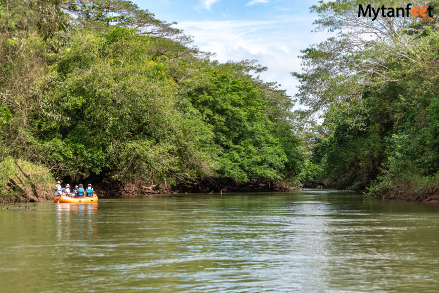 Pure nature safari float - an orange inflatable raft with 6 people floating down a serene river in Costa Rica