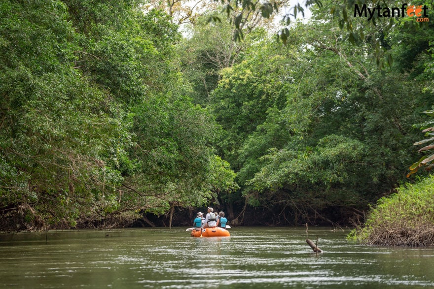 A group of people on a raft, floating down a river surrounded by rainforest in Costa Rica, doing a safari float tour 