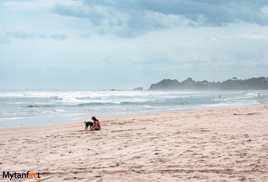 A woman and a dog playing on a beach in Nosara, Costa Rica - Playa Guiones 