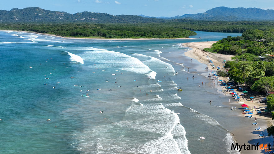 costa rica in november - guanacaste province view of tamarindo beach by drone. Aerial photo of a beach with blue waters, surfers and beach chairs, with a backdrop of a green forest 