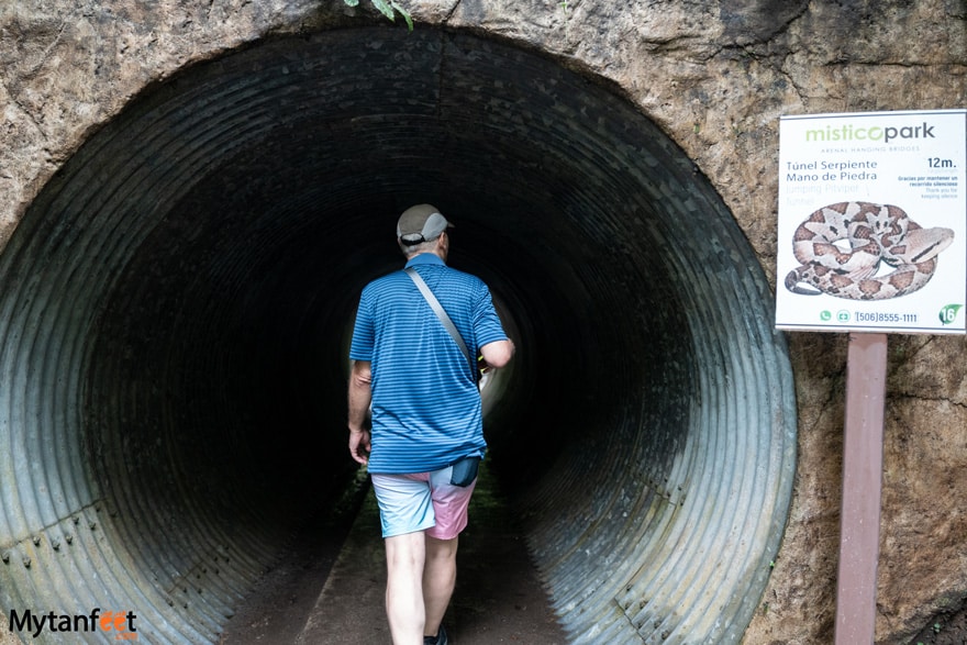 A man wearing a blue shirt and shorts is walking through a tunnel 