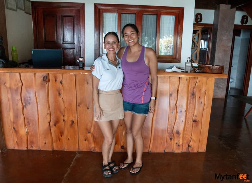 Copa de Arbol Beach & Rainforest Resort, Drake Bay. Two women, one asian and other Costa Rican are standing next to each, smiling and standing in front of a front desk of a hotel