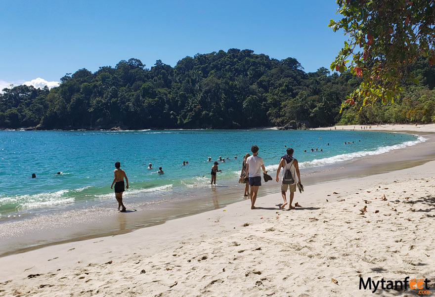 Tourists walking and swimming in the water at Playa Antonio beach, a white sand beach inside Manuel Antonio National Park